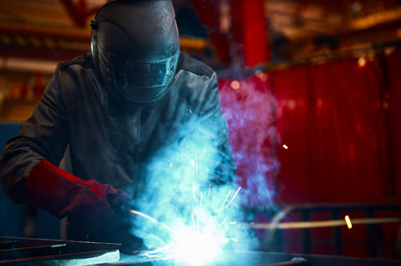 Employee in protective mask and gloves welds metal carcassの写真素材