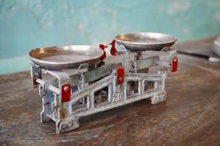 Vintage weighing scale rests gently on a rustic wooden table against a faded wall, capturing the essence of traditional marketplace lifeの写真素材