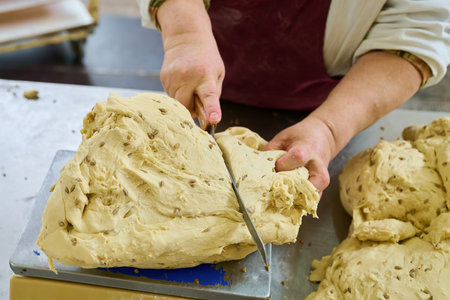 Baker preparing cracker dough with care and precision in a bustling kitchen environment