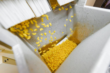 Pasta cascading into the collection hopper at a vibrant manufacturing plant during peak production...
