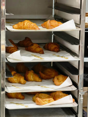 Freshly baked croissants displayed in a bakery during the early morning hours showcasing golden...