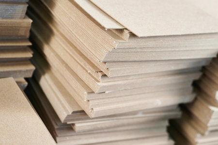 Stacks of thick paperboard ready for transformation into sustainable cardboard boxes at a manufacturing facility in the early morning lightの写真素材