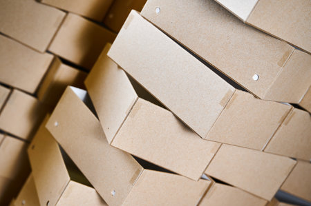 Stacked cardboard box blanks ready for assembly in a bustling manufacturing facilityの写真素材