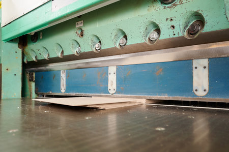Precise cutting of cardboard sheets using guillotine shears in a busy workshop spaceの写真素材