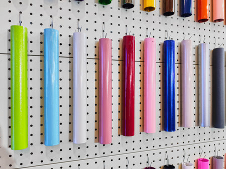 Colorful roll of vinyl sheets hanging on pegs in an artistic workspace showcasing diverse hues and materials for creative projectsの写真素材