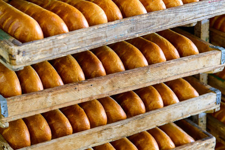 Freshly baked bread rolls resting in wooden trays after being taken out of the oven in a warm bakery