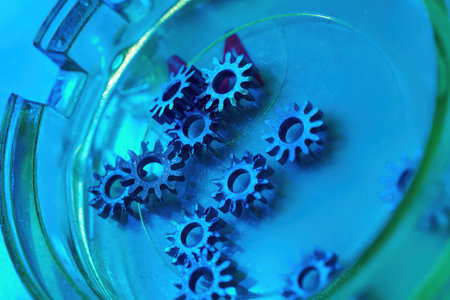 Intricate clockwork gears resting in vibrant hues of blue under soft lighting create a mesmerizing visual harmony of mechanics and artistryの写真素材
