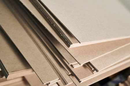Stacks of thick paperboard ready for conversion into sturdy cardboard containers in a busy manufacturing facilityの写真素材
