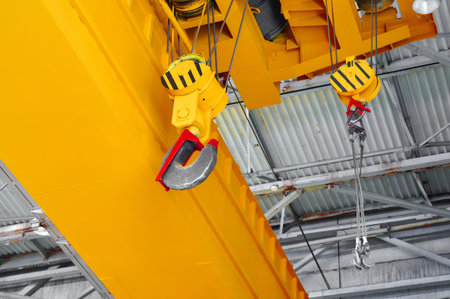 Heavy duty crane lifting equipment in an industrial warehouse setting during daylight hoursの写真素材
