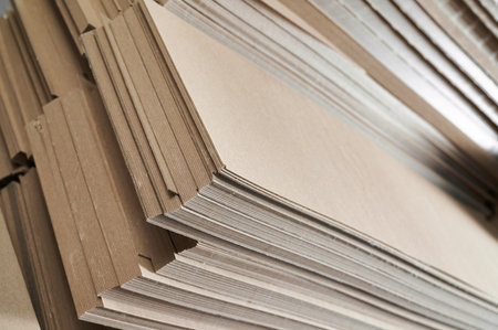 Stacks of thick paperboard ready for production of eco-friendly cardboard box solutions in a bustling factory warehouseの写真素材