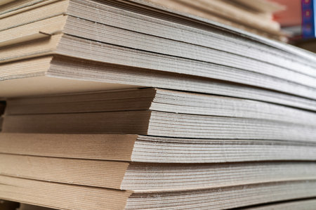 Stacks of thick paperboard ready for cardboard box production in a warehouse environmentの写真素材