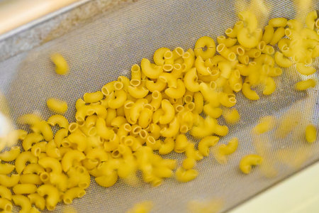 Pasta travels gracefully along a conveyor belt in a bustling kitchen, showcasing the rhythm of culinary excitement and production efficiencyの写真素材