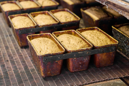 Loaf pans filled with fermented dough awaiting baking in a busy bakery facilityの写真素材