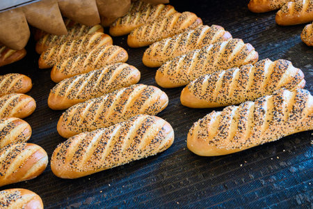 Freshly baked bread rolls emerging from the oven at a bakery early in the morning
