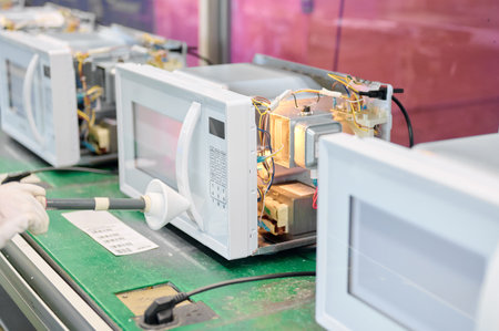 Engineer conducts microwave leakage testing on production line using a detector probe for quality assuranceの写真素材