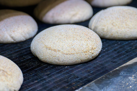 Farmhouse bran dough being formed and prepared for baking at a bakery oven inlet with warm lighting