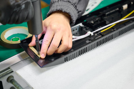 Precision assembly of electronic device components on workstation during daytime in a manufacturing facilityの写真素材