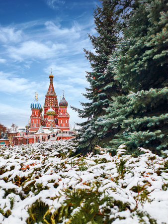 Charming winter view of St. Basils Cathedral surrounded by snow-covered trees and serene landscape...