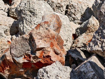 Natural rock formation displaying various textures and colors under bright sunlight at a construction siteの写真素材