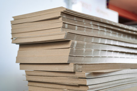 Stacks of thick paperboard waiting for transformation into sturdy cardboard boxes in a manufacturing facilityの写真素材