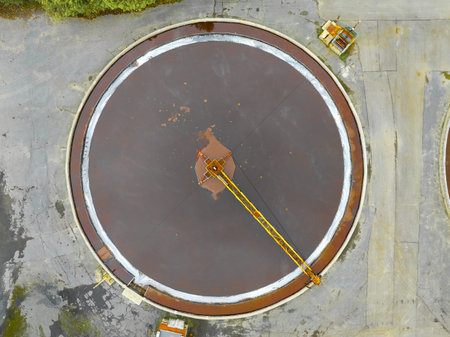 Sewage treatment plant circular tank with crane at work in an industrial area during daylight