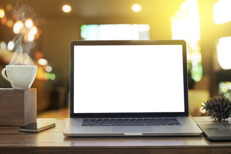 Laptop blank screen on desk in morning sunshine coffee shopの写真素材