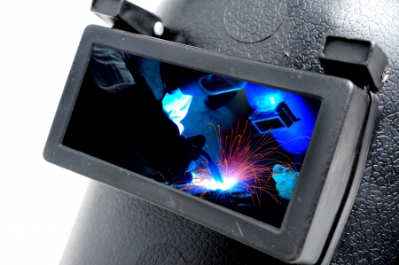 Closeup glass of protective welding mask with welders inside 