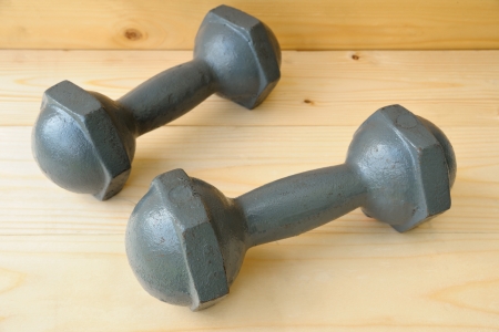 old dumbbell isolated on wooden plankの写真素材