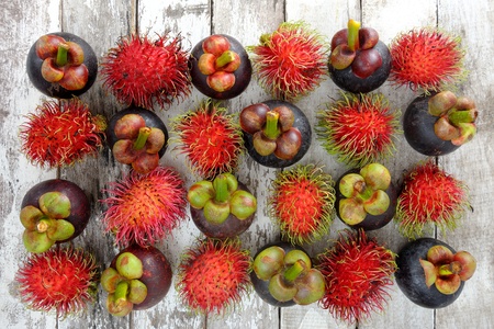 fresh mangosteens and rambutans arrange on wooden plankの写真素材