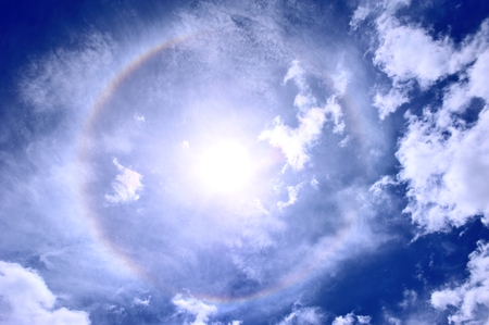 Sun halo with blue sky and white cloudの写真素材
