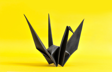 The black origami bird on yellow paperの写真素材