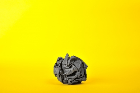 black paper ball isolate on yellowの写真素材