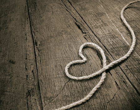 jute rope in heart shaped isolated on wooden backgroundの写真素材
