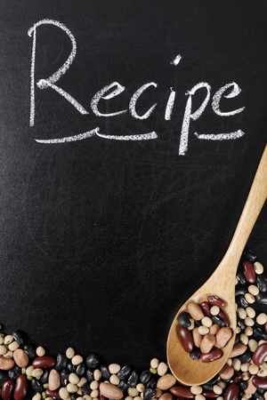 the word Recipe on chalk board with beans and wooden spoonの写真素材