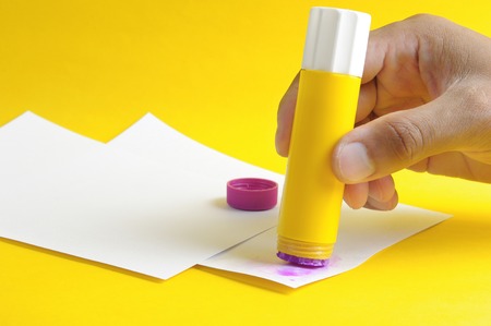 applying purple glue stick to white paperの写真素材