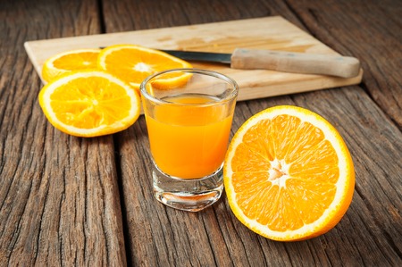 Ripe orange and orange juice on wooden tableの写真素材