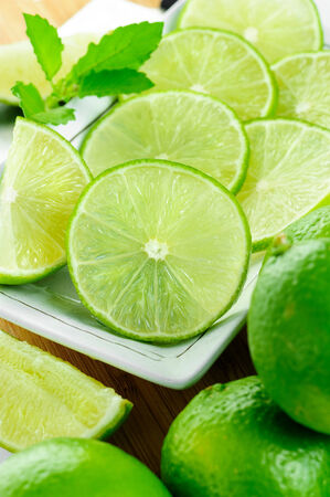 closeup sliced fresh green limes in white plateの写真素材