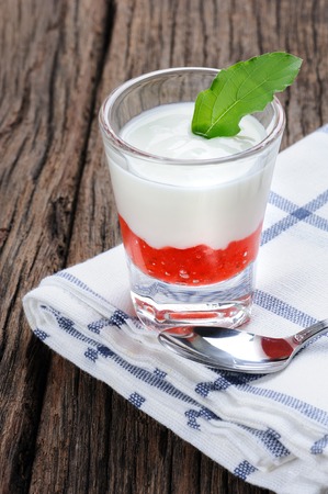 fresh natural yogurt with strawberry jam in glass on wooden plankの写真素材
