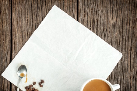 folded blank white paper on wooden table with coffee cupの写真素材