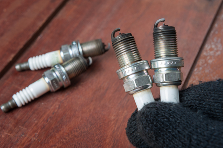 used spark plug with soot in technician hand