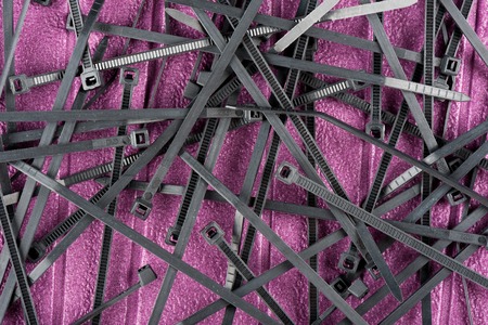 heap of black cable ties on purple background