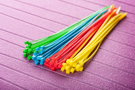 heap of colorful cable ties on purple background