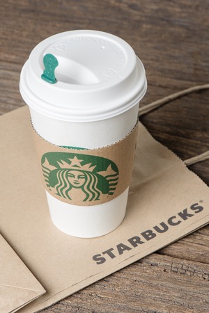 BANGKOK, THAILAND - FEBRUARY 26, 2015: White paper cup with sleeve with Starbucks logo. Starbucks is the world's largest coffee house with over 20,000 stores in 61 countries.のeditorial素材