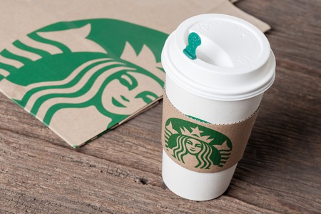 BANGKOK, THAILAND - FEBRUARY 26, 2015: White paper cup with sleeve with Starbucks logo. Starbucks is the world's largest coffee house with over 20,000 stores in 61 countries.のeditorial素材