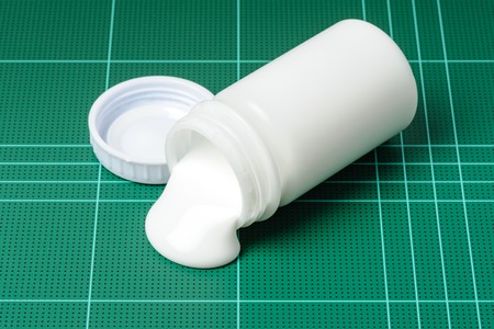 closeup white latex adhesive spilling on cutting matの写真素材