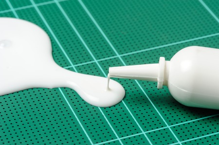 closeup white latex adhesive spilling on cutting matの写真素材