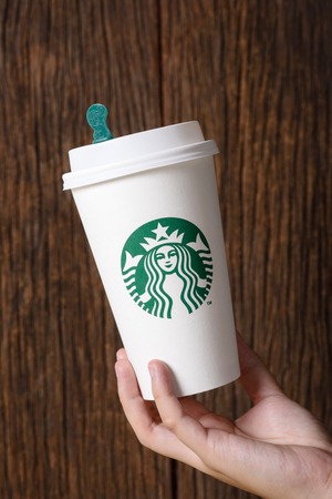 BANGKOK, THAILAND - MARCH 17, 2015: White paper cup with Starbucks logo in hand. Starbucks is the world's largest coffee house with over 20,000 stores in 61 countries.のeditorial素材