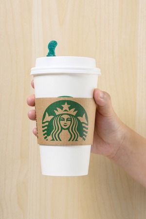 BANGKOK, THAILAND - MARCH 17, 2015: White paper cup with Starbucks logo in hand. Starbucks is the world's largest coffee house with over 20,000 stores in 61 countries.のeditorial素材