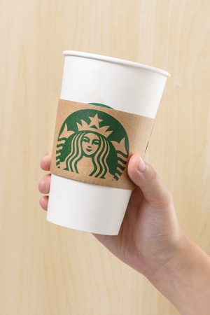 BANGKOK, THAILAND - MARCH 17, 2015: White paper cup with Starbucks logo in hand. Starbucks is the world's largest coffee house with over 20,000 stores in 61 countries.のeditorial素材