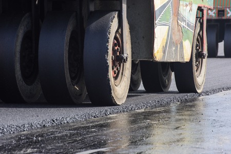 closeup wheel of roller compactor at asphalt road construction siteの写真素材